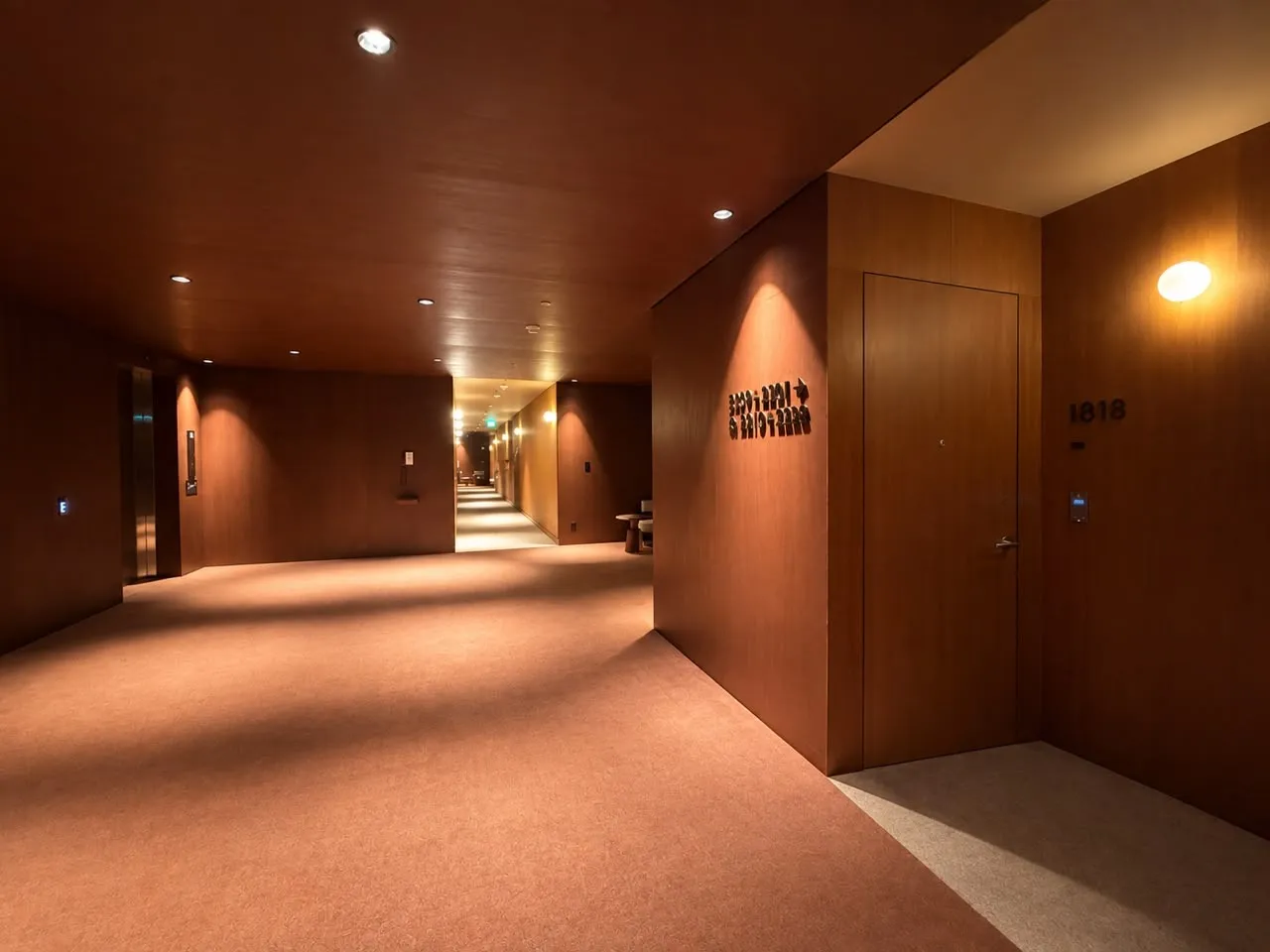 Pasillo de hotel con muros y techo de madera y puerta de habitación